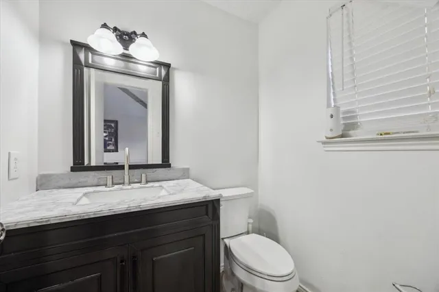 a bathroom with a granite countertop toilet sink and mirror