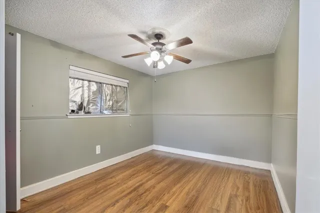 a view of an empty room with window and wooden floor