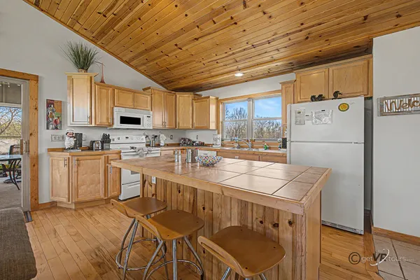 a kitchen with kitchen island granite countertop a refrigerator a stove a sink dishwasher and white cabinets with wooden floor
