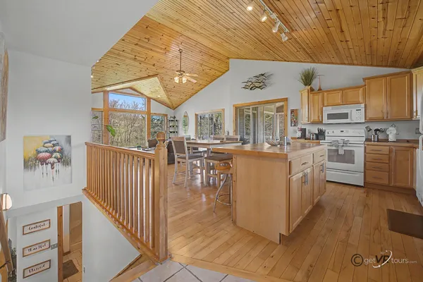 a living room with stainless steel appliances kitchen island granite countertop a table chairs and a view of living room