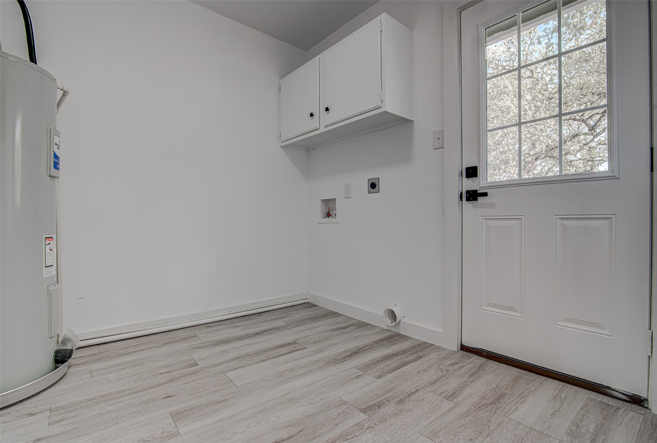 207 Haley Road Johnson City, TX 78636 - Photo 23 of 31 Functional utility space with durable wood-look flooring and convenient overhead cabinetry.