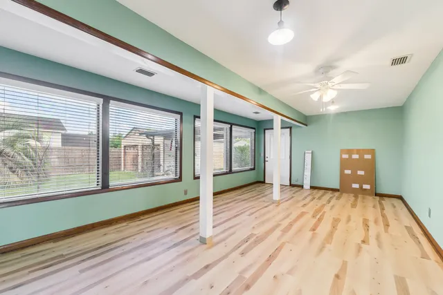 a view of an empty room with a window and wooden floor