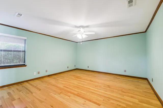 an empty room with a chandelier fan and windows