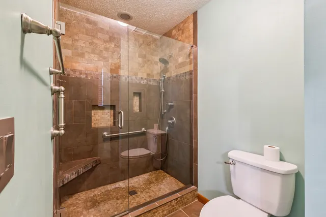 a bathroom with a granite countertop bathtub shower and toilet