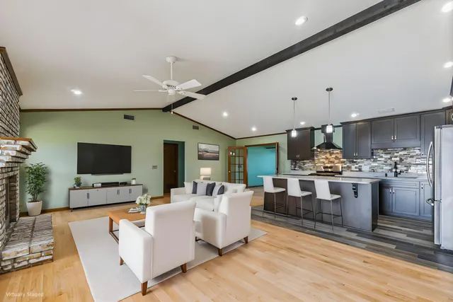 a living room with furniture a flat screen tv and kitchen view