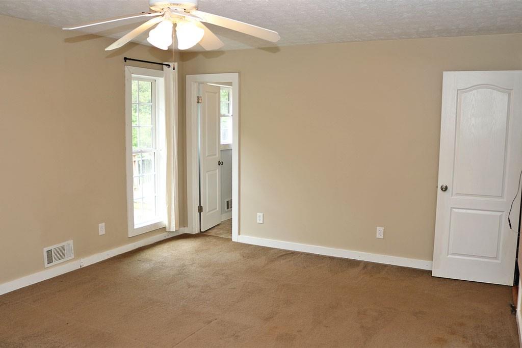 3129 Etchison Road Loganville, GA 30052 - Photo 17 of 58 an empty room with a chandelier fan and windows