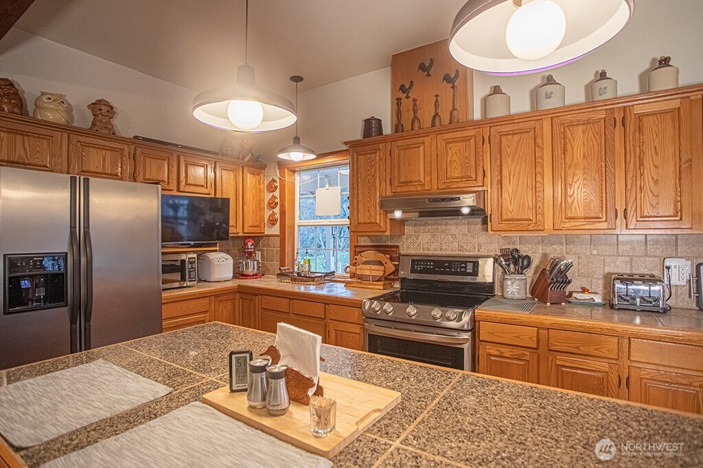 951 Bulman Road Southeast Port Orchard, WA 98366 - Photo 8 of 39 a kitchen with stainless steel appliances granite countertop a sink refrigerator stove and microwave