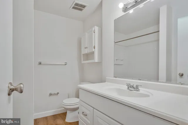 a bathroom with a granite countertop sink toilet and mirror