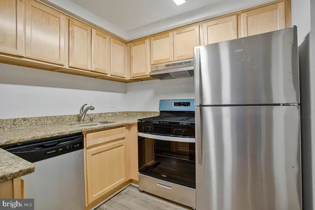 a kitchen with granite countertop a refrigerator stove and cabinets