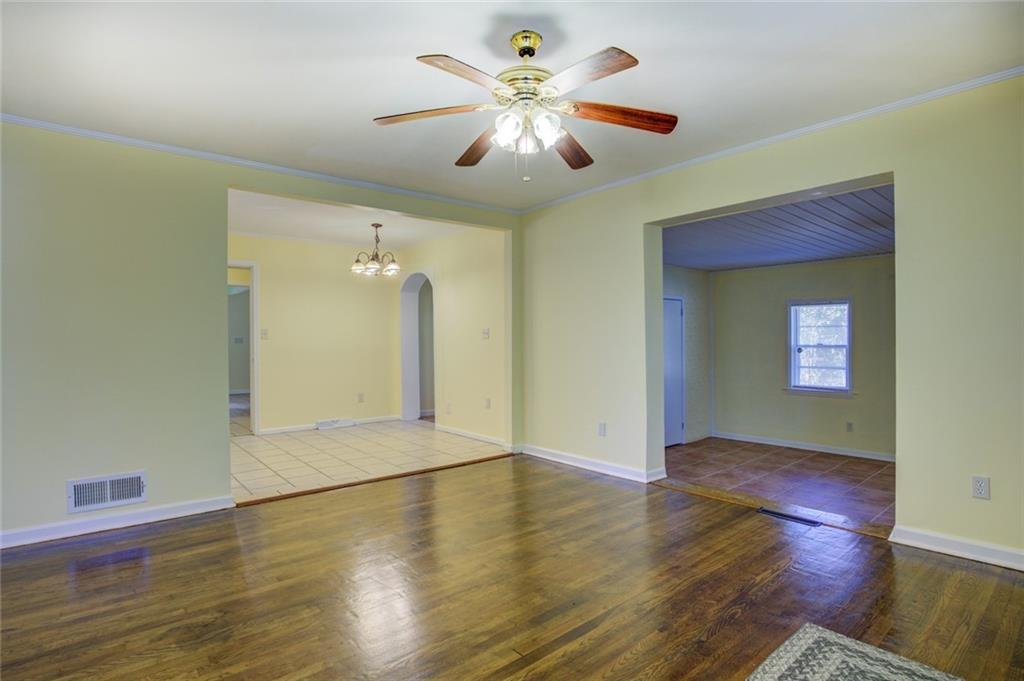 9174 Flat Shoals Road Southwest Covington, GA 30014 - Photo 4 of 25 an empty room with wooden floor and a ceiling fan