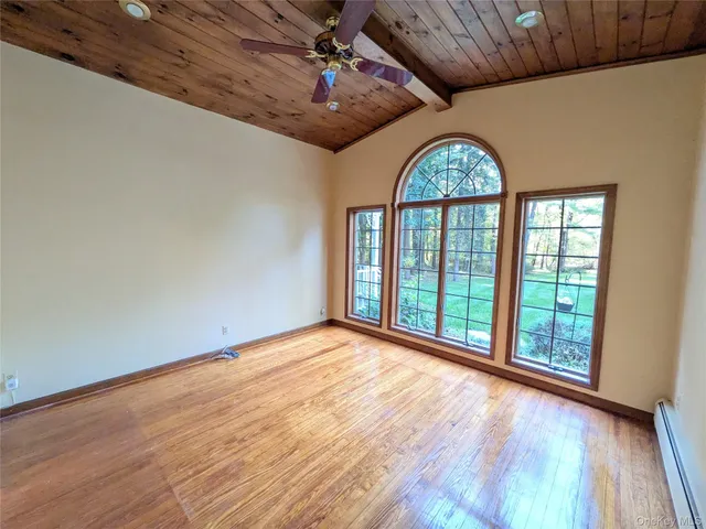 a view of an empty room with a window and wooden floor