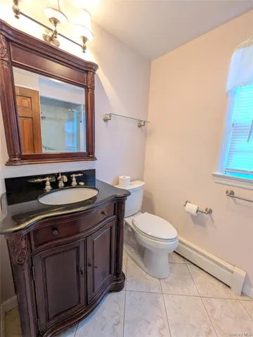 a bathroom with a granite countertop toilet sink and mirror