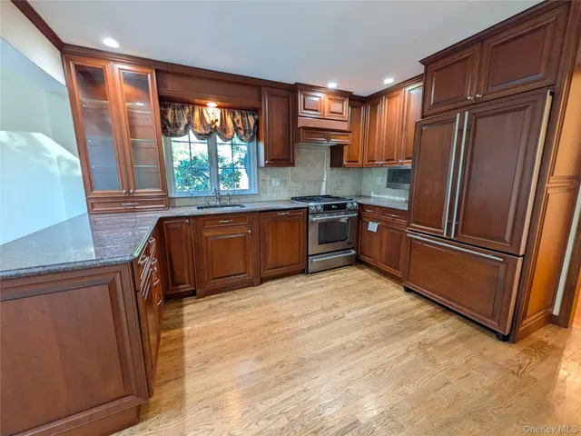 a kitchen with granite countertop stainless steel appliances a refrigerator cabinets and a sink