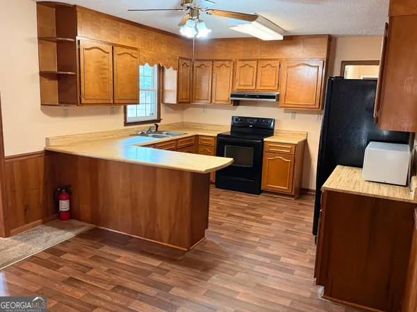 a kitchen with stainless steel appliances granite countertop a refrigerator a sink dishwasher a stove with wooden cabinets and floor