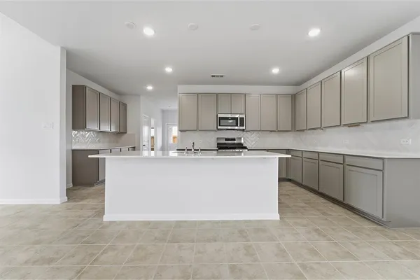 a large white kitchen with kitchen island sink a stove a cabinets and a refrigerator