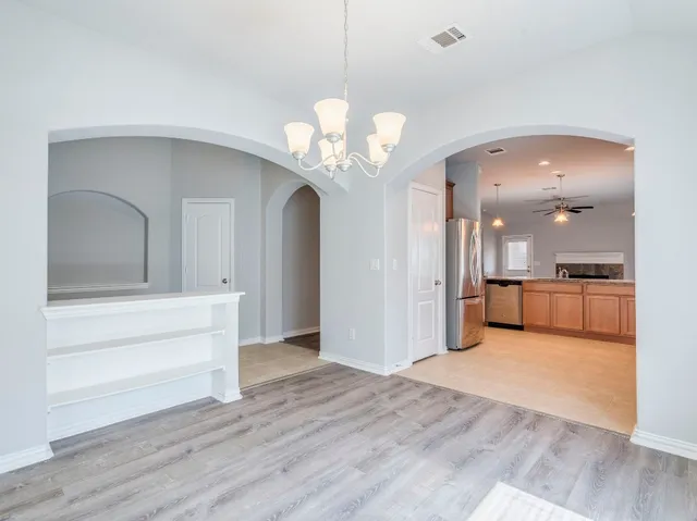 a view of a hallway with wooden floor and a kitchen