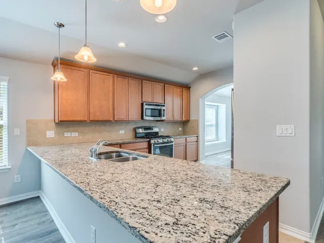 a kitchen with granite countertop a sink a counter top space appliances and cabinets