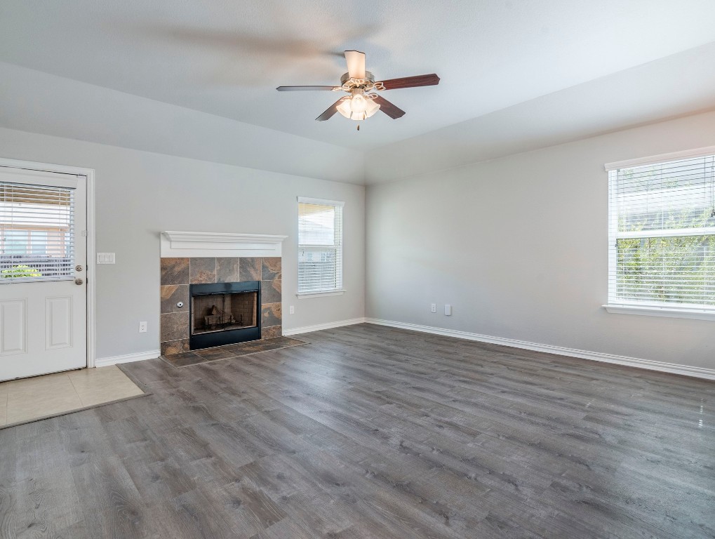 225 Razzmatazz Trail Buda, TX 78610 - Photo 9 of 28 an empty room with windows fireplace and a ceiling fan