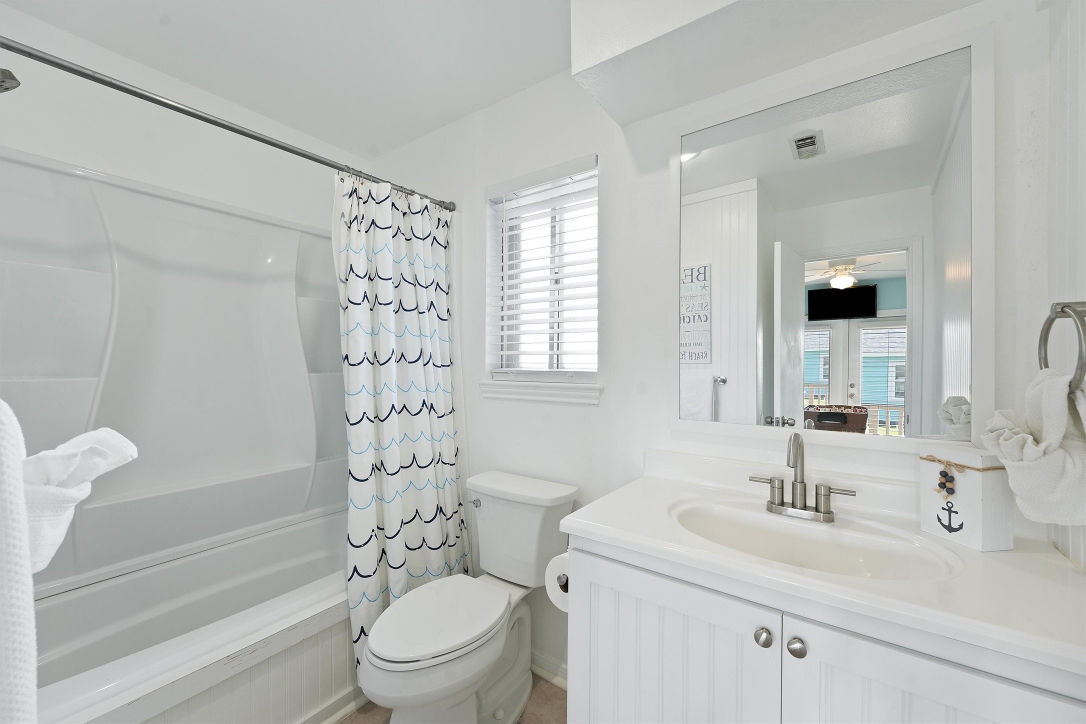 17607 Termini-San Luis Pass Road Galveston, TX 77554 - Photo 29 of 42 The attached en-suite bathroom is both practical and charming, featuring a full bathtub and a shower. With its crisp white fixtures, it maintains a fresh and clean aesthetic that matches the rest of the room.