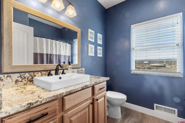 a bathroom with a granite countertop sink a toilet and a mirror