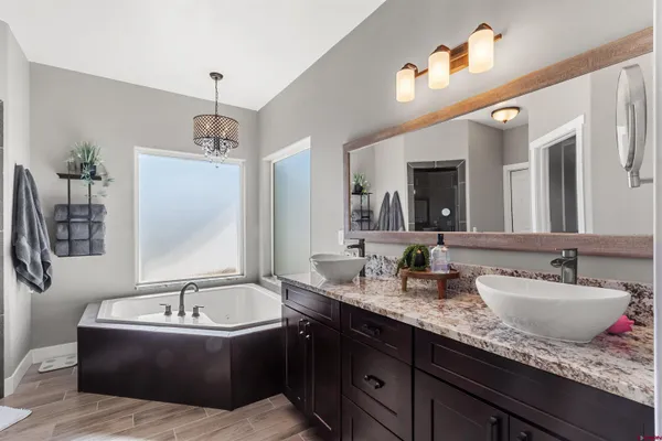 a bathroom with a granite countertop tub sink and mirror