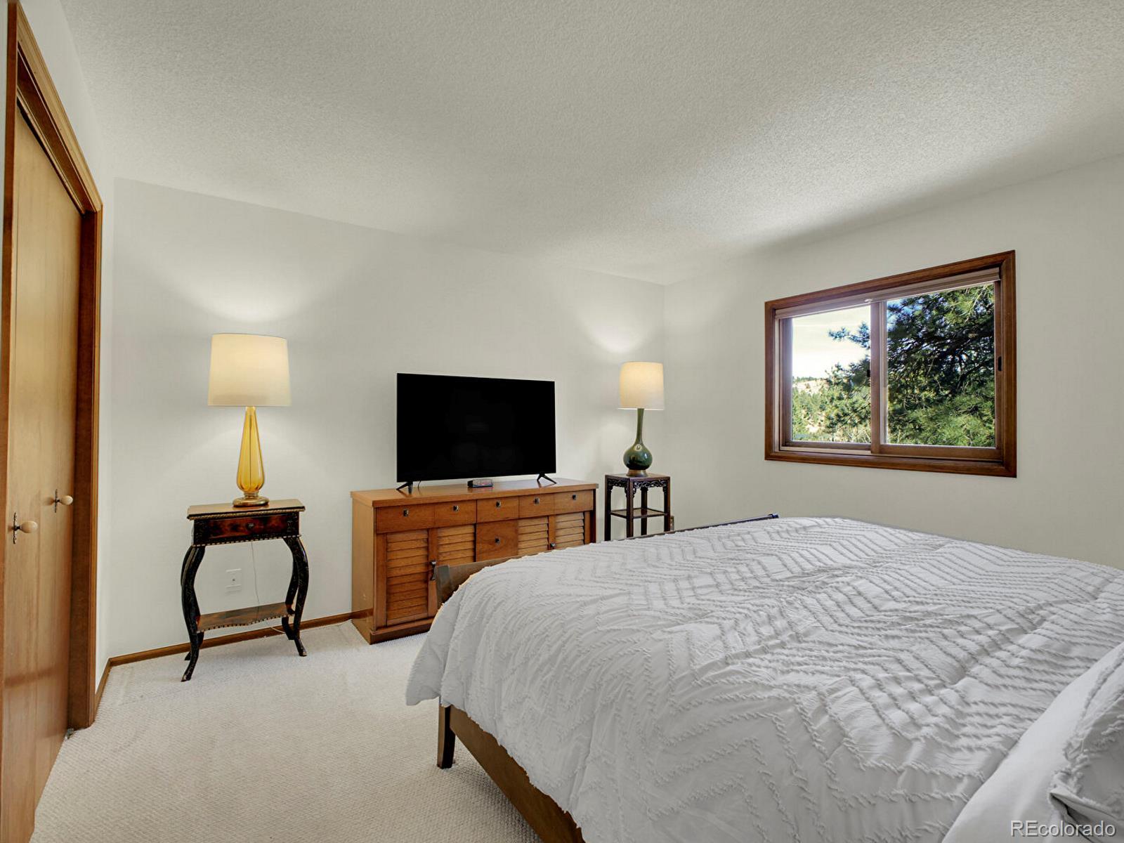 638 Impala Trail Bailey, CO 80421 - Photo 18 of 50 a bedroom with a bed and a flat screen tv