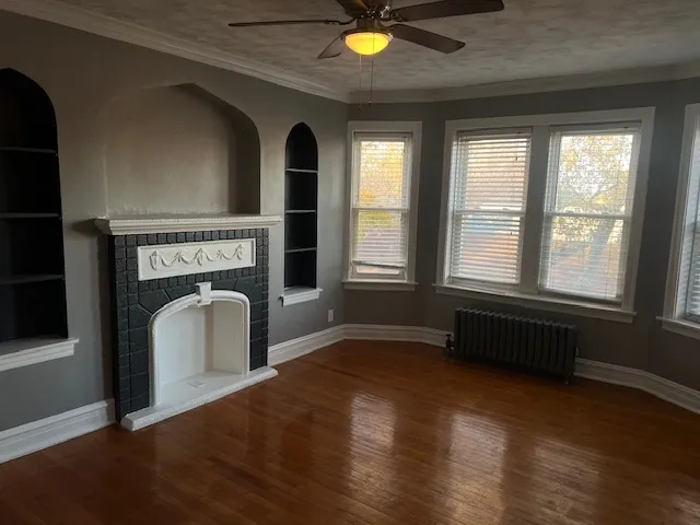 a view of an empty room with exposed radiator and fireplace