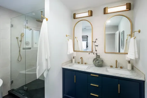 a bathroom with a granite countertop sink a mirror and shower