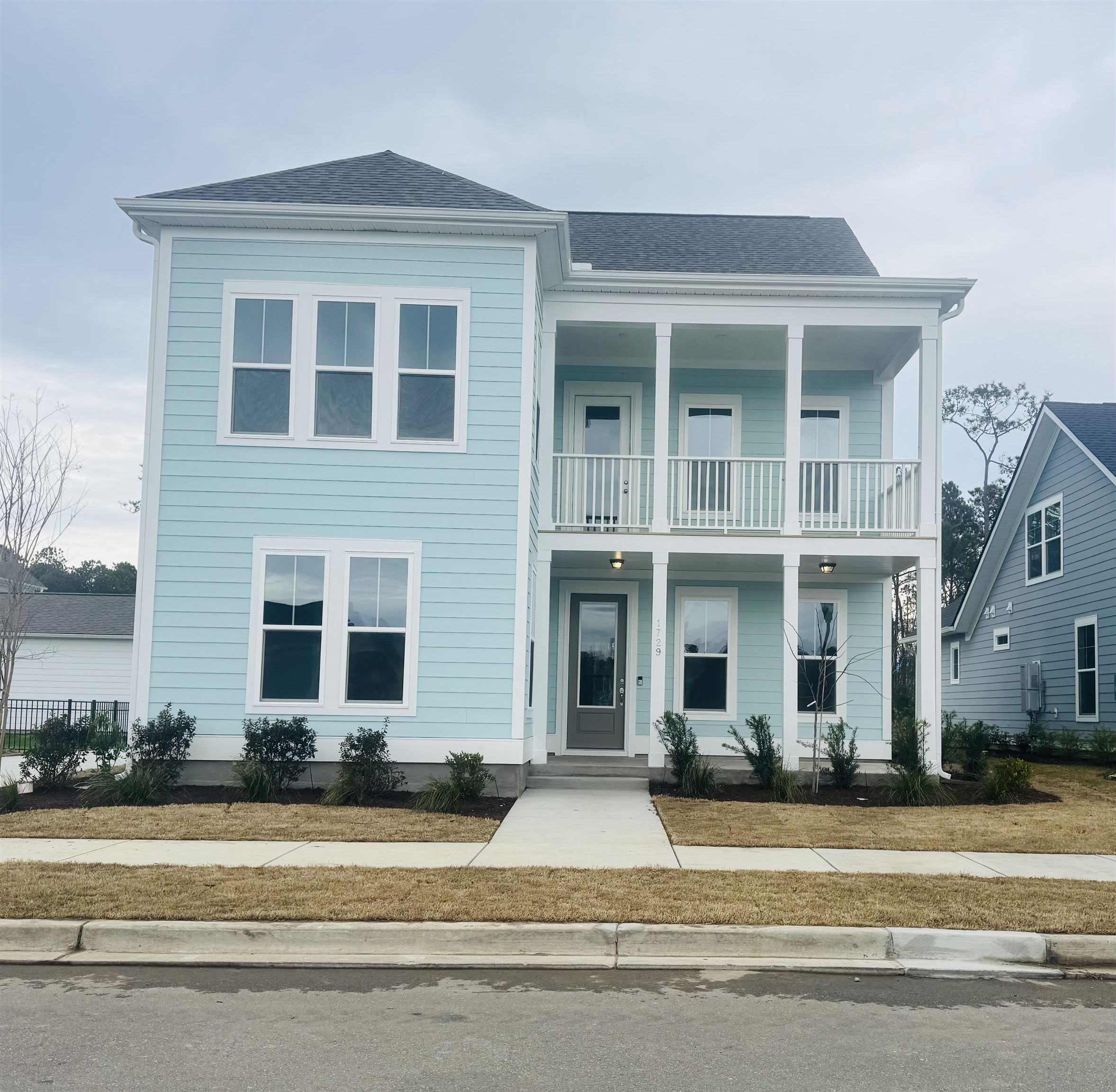 View of front of property with covered porch, roof with shingles, and a balcony