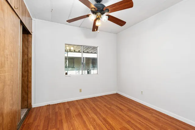 a view of an empty room with window and wooden floor