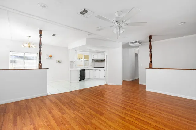 a view of an empty room with wooden floor and a ceiling fan