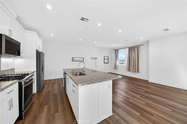 a kitchen with granite countertop cabinets stainless steel appliances a sink and a large window