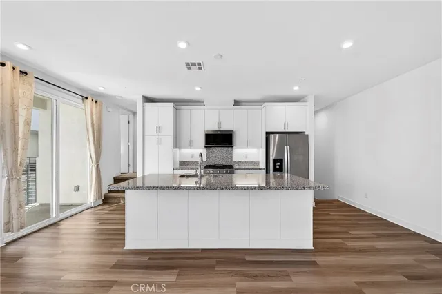 a large kitchen with granite countertop a large counter top stainless steel appliances and cabinets