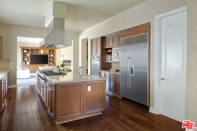 a kitchen with stainless steel appliances granite countertop a stove a refrigerator and a wooden floors