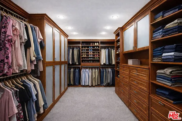 a view of walk in closet with clothes and shoes