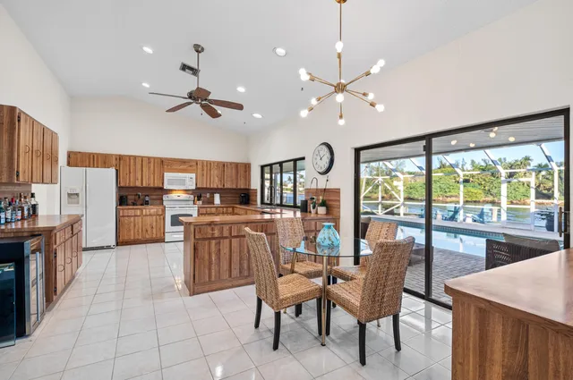a kitchen with stainless steel appliances kitchen island granite countertop a table chairs and a refrigerator