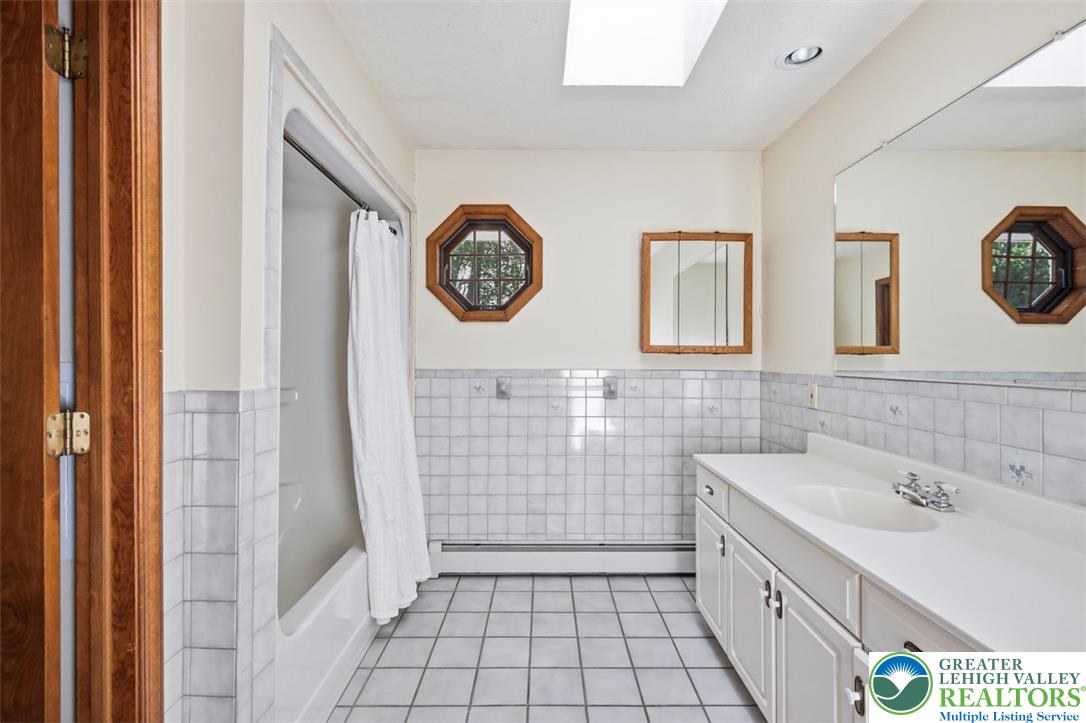 123 Meadow Road Blakeslee, PA 18610 - Photo 26 of 53 A spacious bathroom features classic wall tilework, wood accents, and natural light from a skylight.