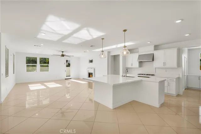 a large white kitchen with kitchen island granite countertop a large window and white cabinets