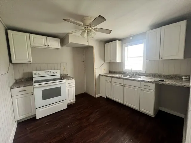 a kitchen with granite countertop white cabinets and white appliances