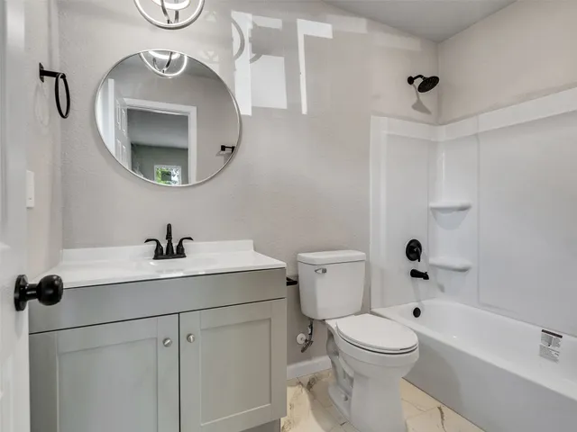 a bathroom with a toilet sink vanity tub and mirror