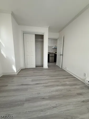 a view of a kitchen and empty room with wooden floor