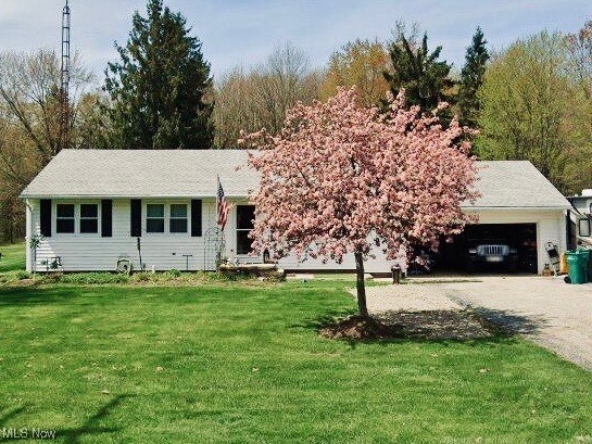 Ranch-style house with a front yard, a garage, and driveway