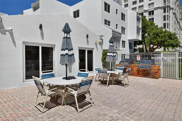 a kitchen with stainless steel appliances granite countertop a stove a refrigerator a sink a dining table and chairs with wooden floor