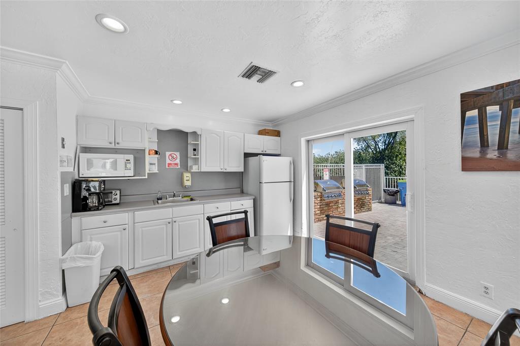 2850 Northeast 14th Street, Unit 410B Pompano Beach, FL 33062 - Photo 23 of 25 a kitchen with stainless steel appliances granite countertop a stove a refrigerator a sink a dining table and chairs with wooden floor