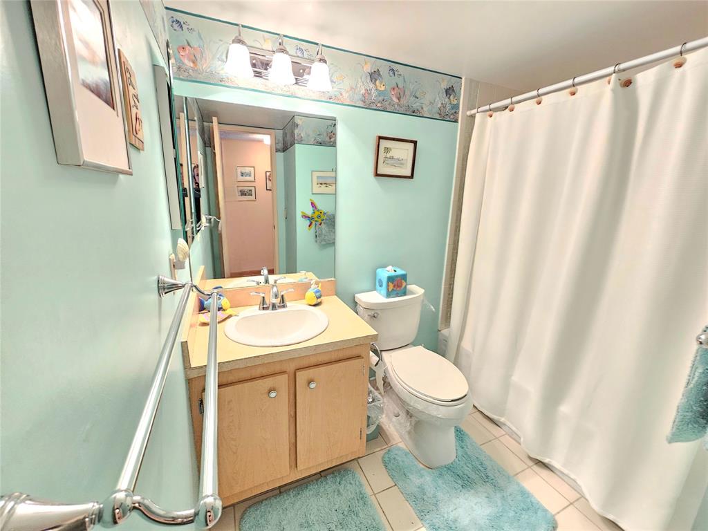 2850 Northeast 14th Street, Unit 410B Pompano Beach, FL 33062 - Photo 10 of 25 a bathroom with a sink a toilet and shower curtain