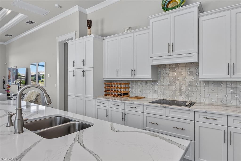 6387 Warwick Avenue Naples, FL 34113 - Photo 11 of 40 Kitchen featuring beautiful backsplash, quartz counters, white cabinets