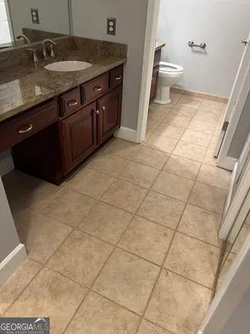 a bathroom with a granite countertop toilet sink and mirror