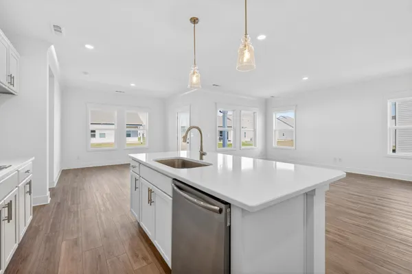 a kitchen with white cabinets a sink dishwasher and a stove with wooden floor