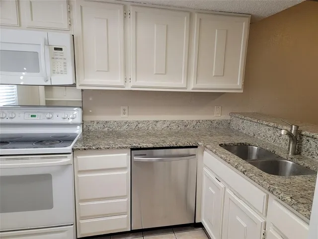 a kitchen with granite countertop white cabinets and white appliances