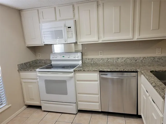 a kitchen with granite countertop white cabinets and stainless steel appliances